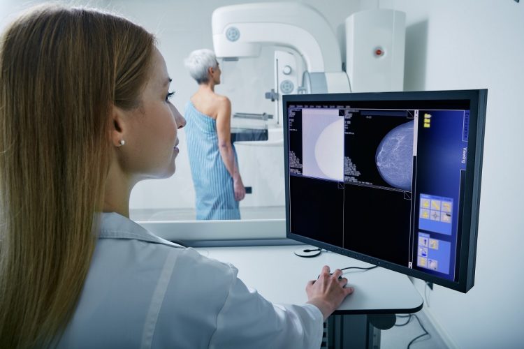 Medical technician taking mammogram exam to female patient. Mature woman undergoing breast screening or mammography